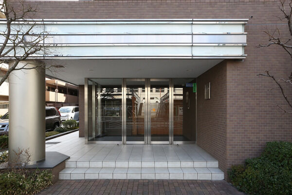 シャンパンゴールドの柱と白い庇が印象的なエントランス。		