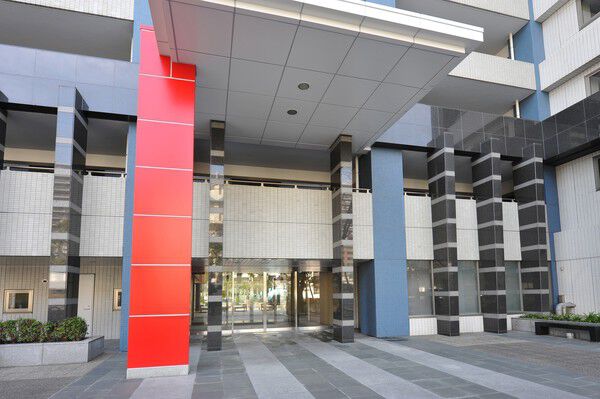 赤色の飾り柱と奥に立ち並ぶツートンストライプの御影石が印象的なエントランス。	