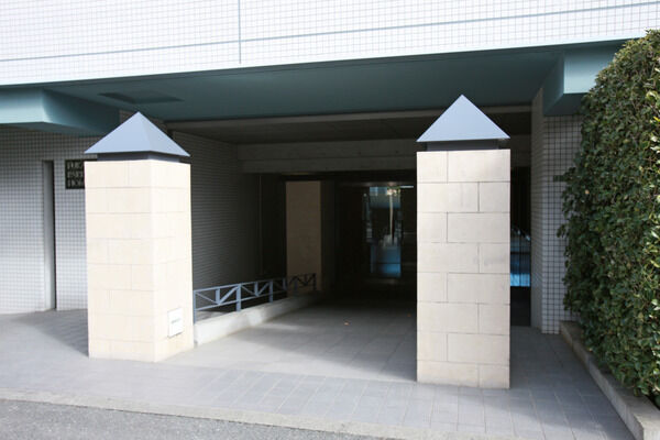 趣のある門柱とゆたかな植栽に彩られた奥行きあるスロープのアプローチ。