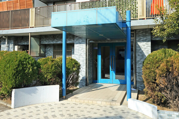 水色の柱・天井が印象的なエントランスアプローチ。