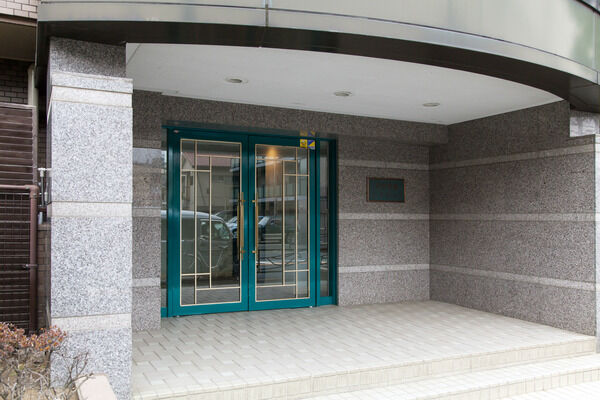 エントランス周辺は天然石とグリーンの扉の調和がとれ、高級感を感じさせられる。