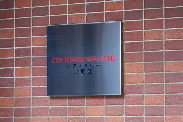 赤茶色のタイルに、マンションのプレートが配されています。