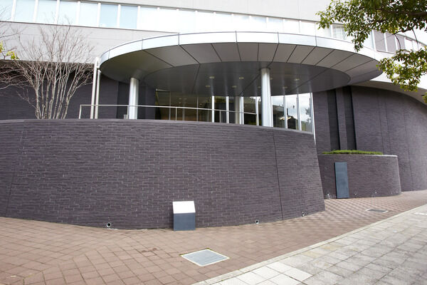 ダークグレーのタイルがゆったりとした円形を描く優しいフォルムのアプローチ。