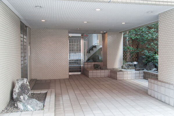 床のグレー、壁は白い磁器タイル、入口の框ドアの黒が調和。		