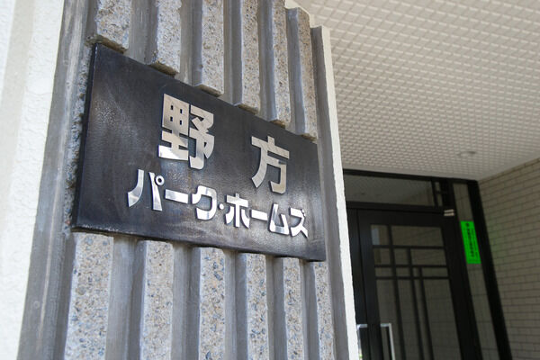 【野方パーク・ホームズ】ダークグレーと白の配色で大人のイメージをつくりあげるエントランス。		