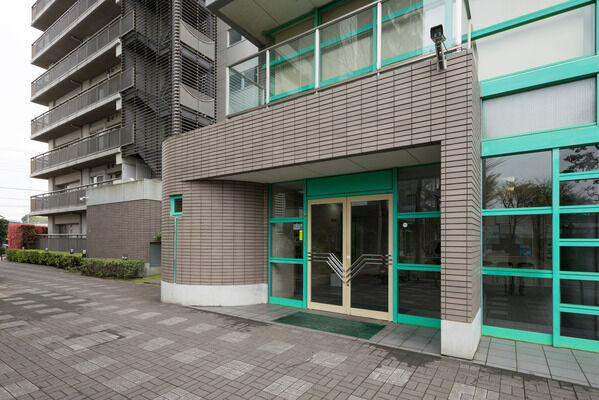 ガラスドアとタイル張りの壁が、清潔感と品格を表現するエントランス。