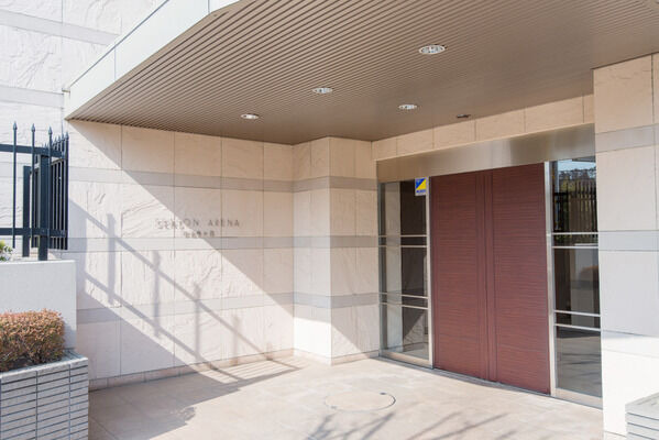 木調のドアが安らぎ感を与えます。中には2層吹き抜けのエントランスホールが。