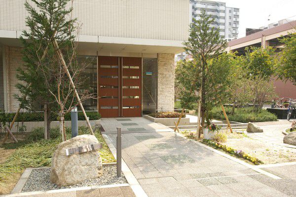 シンプルツリーを配した豊かな緑と庭園を感じる自然石のモニュメントのエントランス。