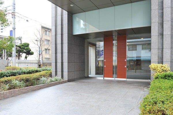 建物全体を包むように配された緑の奥には木調ドアとガラスウォールを採用。		