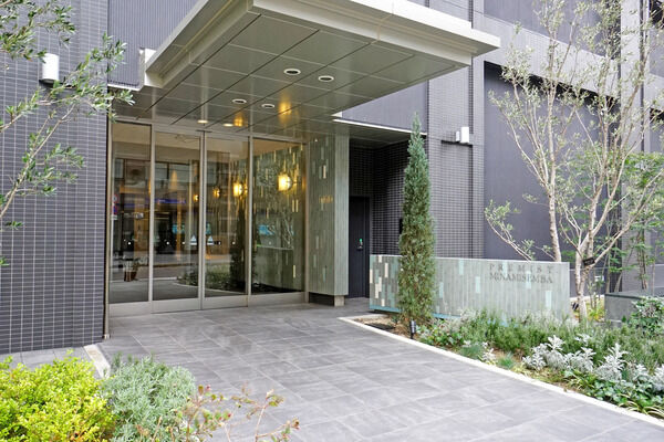 エントランスには長い庇、プレイロットには箱庭のような設えで、木々と草花を配置。		