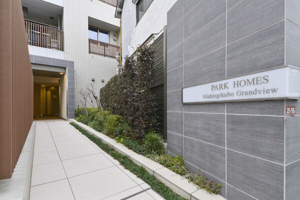 淡色タイルと木調格子、緑の薫る植栽があたたかくお出迎えする東口アプローチ。		