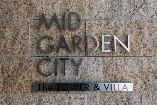 上質感ある石材を使用した壁面に飾られたスタイリッシュな金属製ネームプレート。